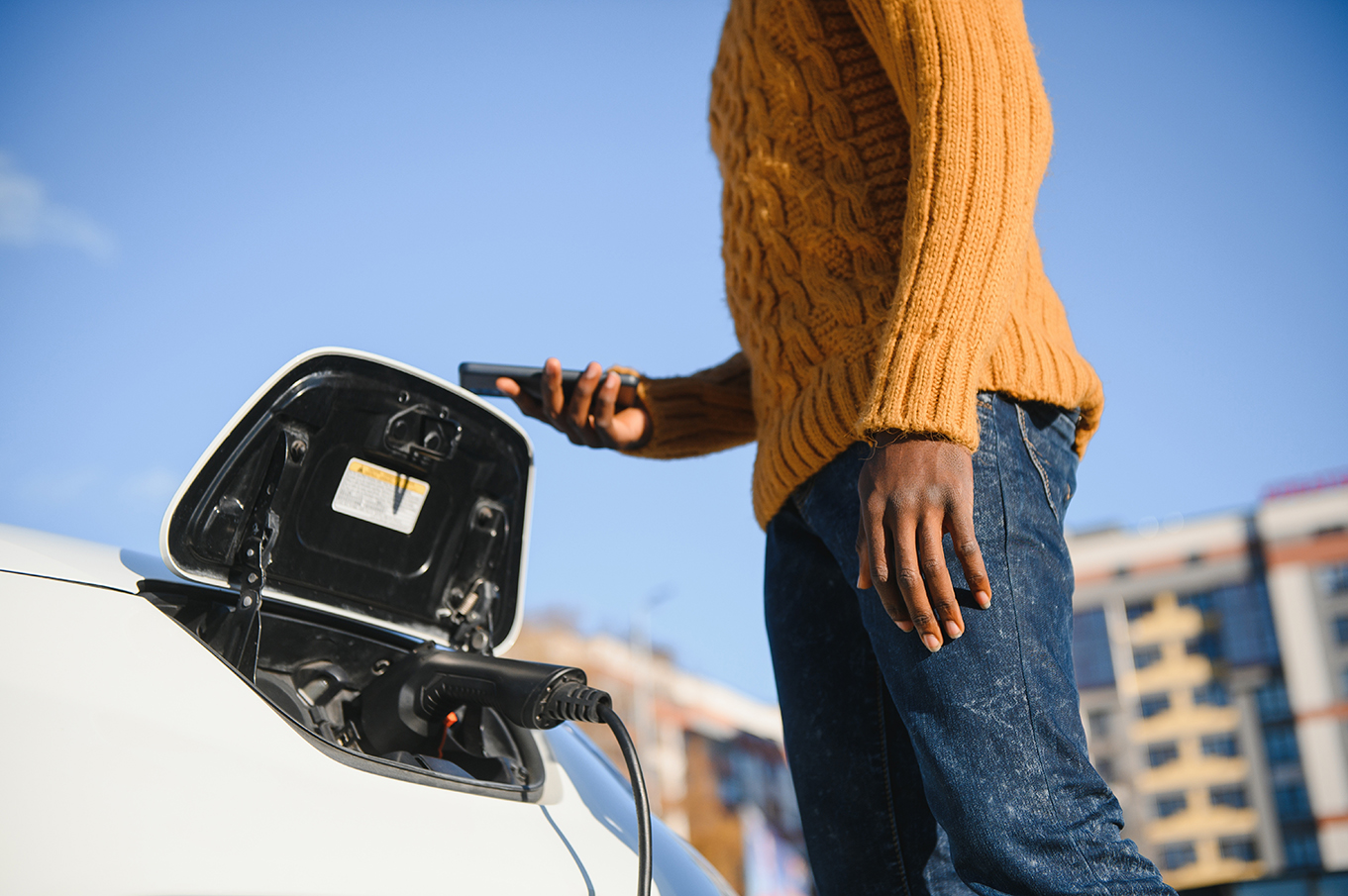 African American man charging his electric car.